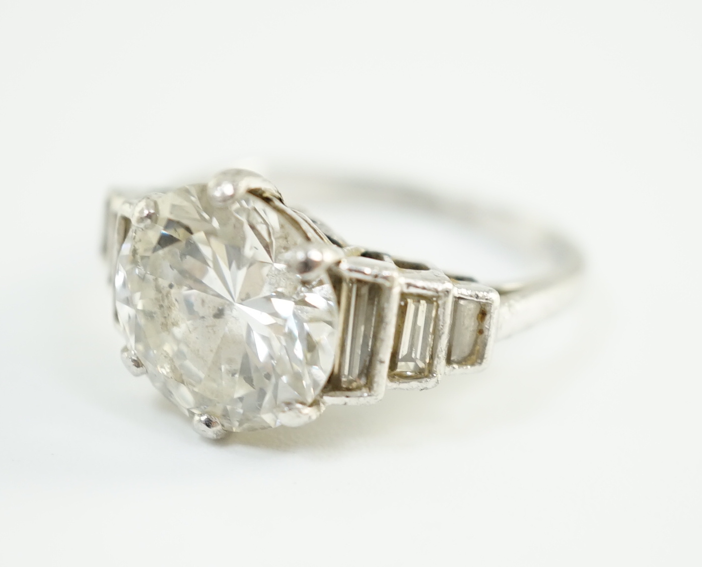 An Art Deco platinum and single stone diamond set ring, with six stone graduated baguette cut diamond set shoulders